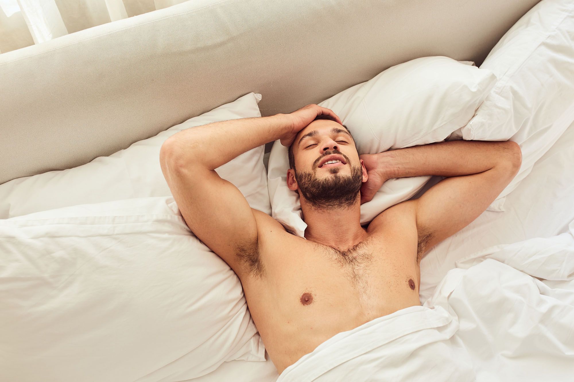 Mann liegt im Bett und genießt einen Blowjob