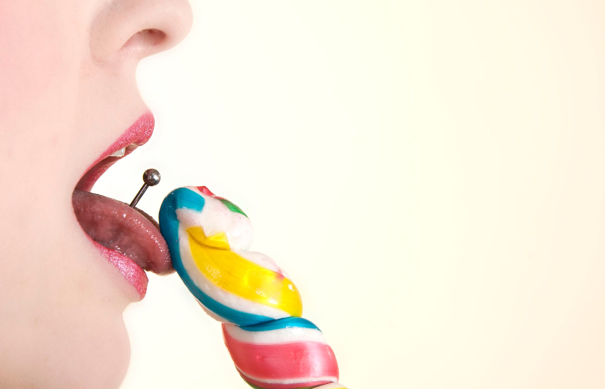 Frau mit Zungenpiercing leckt an einem Lolli