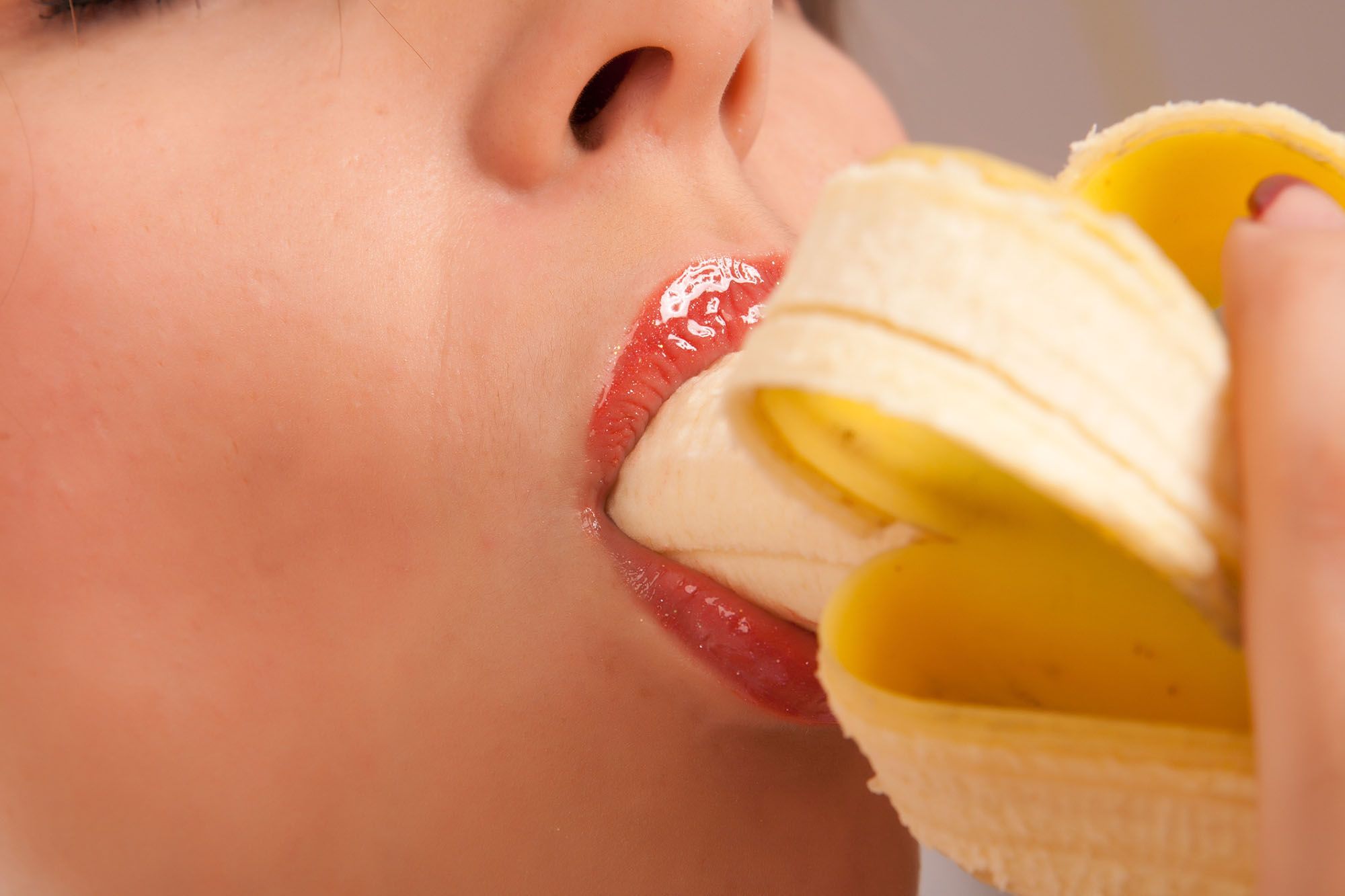 Frau schiebt sich eine Banane weit in den Mund