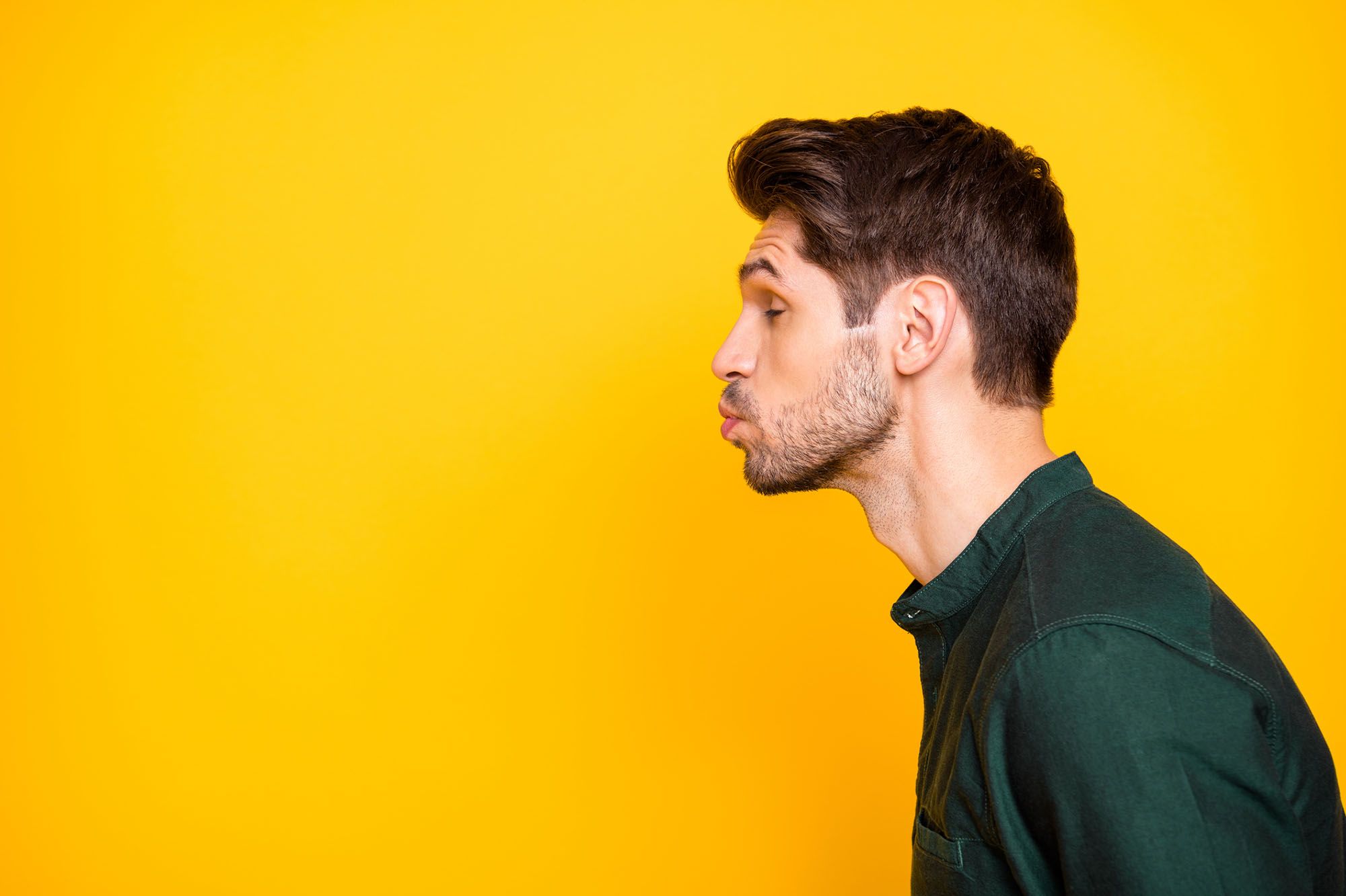 Mann steht mit einem Kussmund vor einer gelben Wand