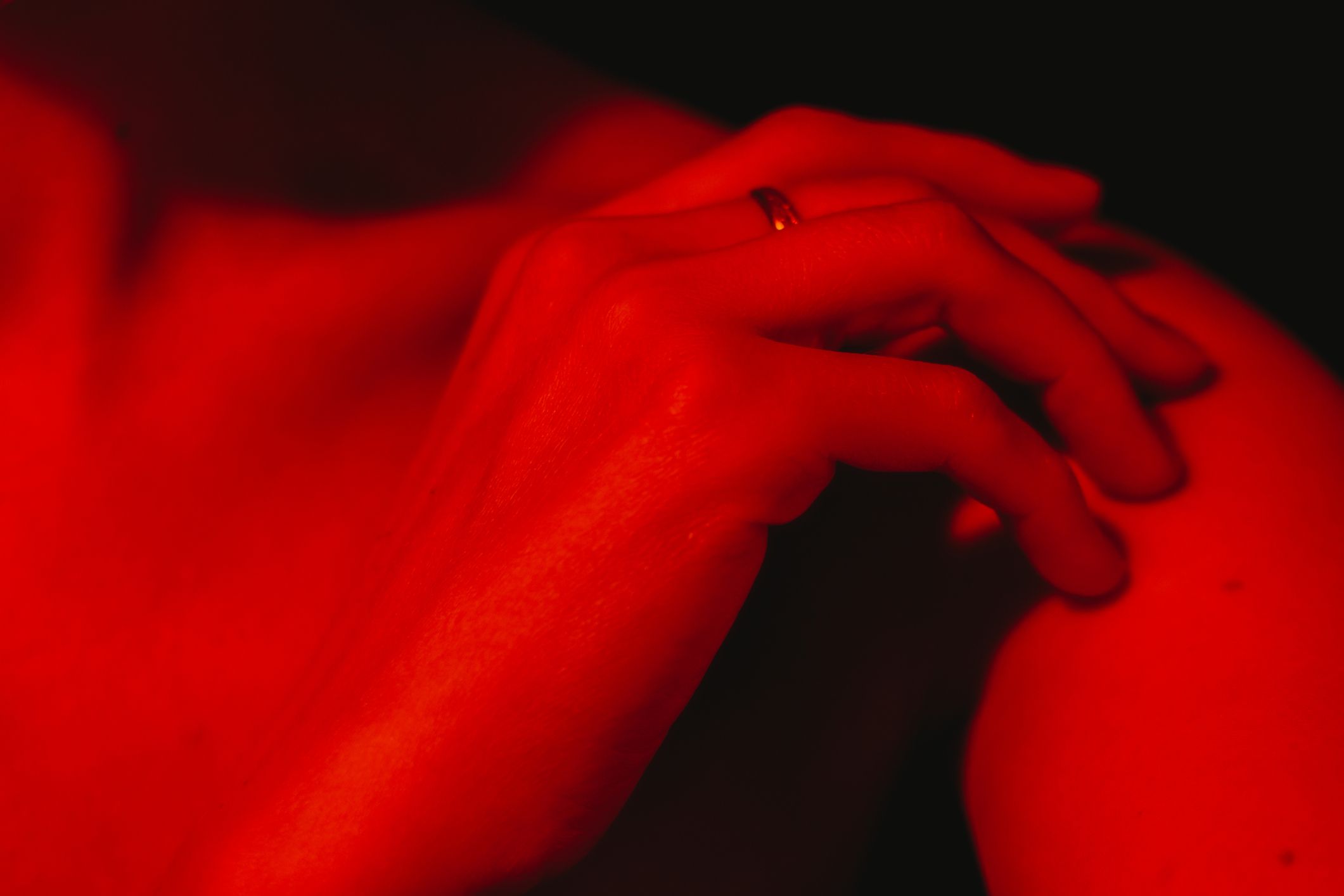 Eine Hand, die auf einem Körper ruht, ist in rotem Licht erleuchtet.