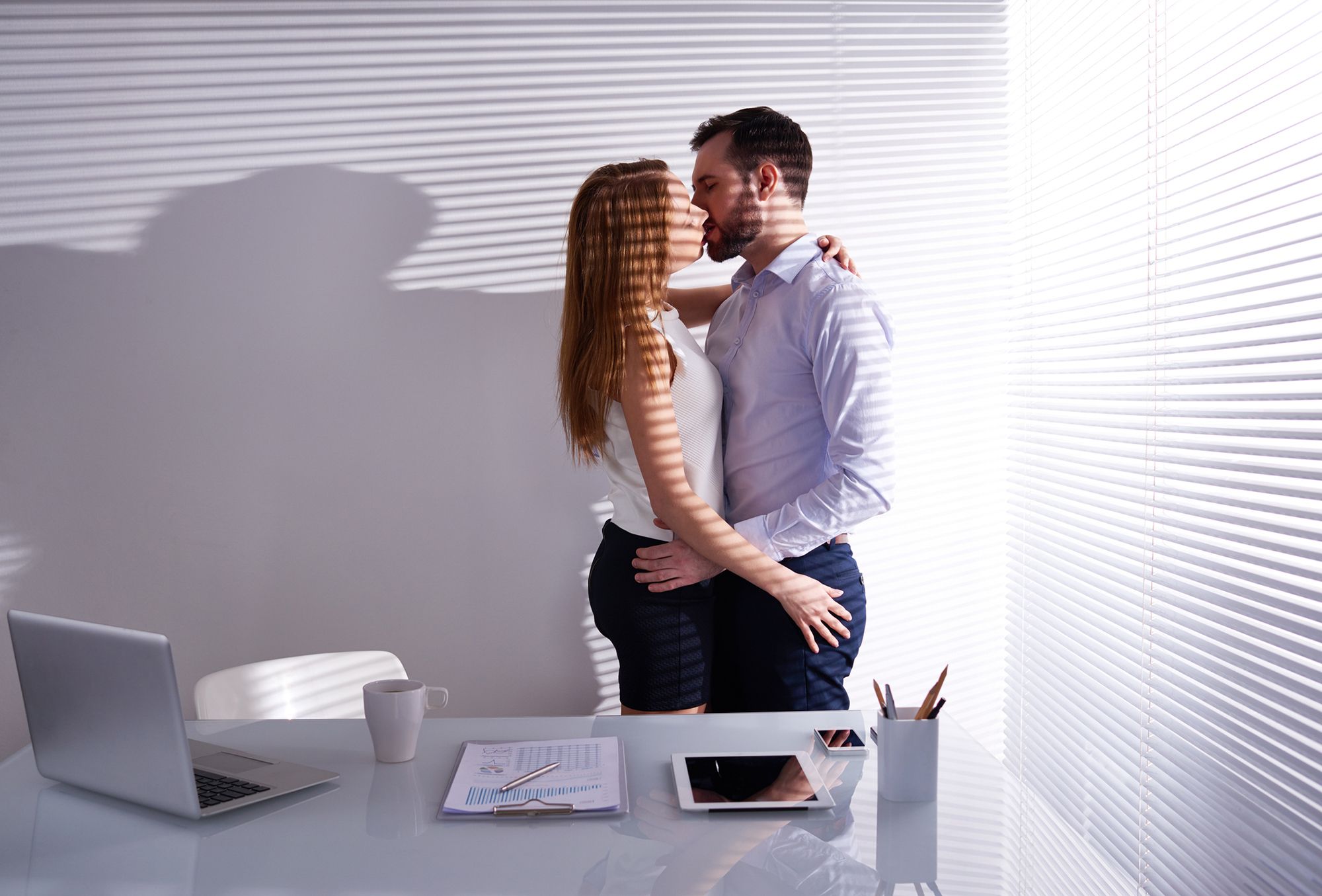Mann und Frau küssen sich in einem Büro