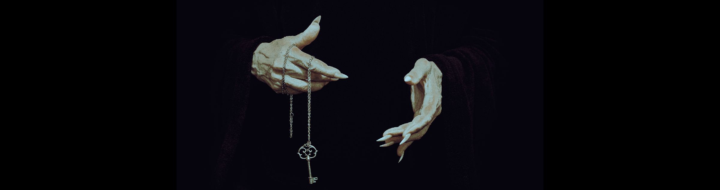 Zwei Hände, mit langen spitzzulaufenden Nägeln halten eine Kette, an der ein Schlüssel befestigt ist.