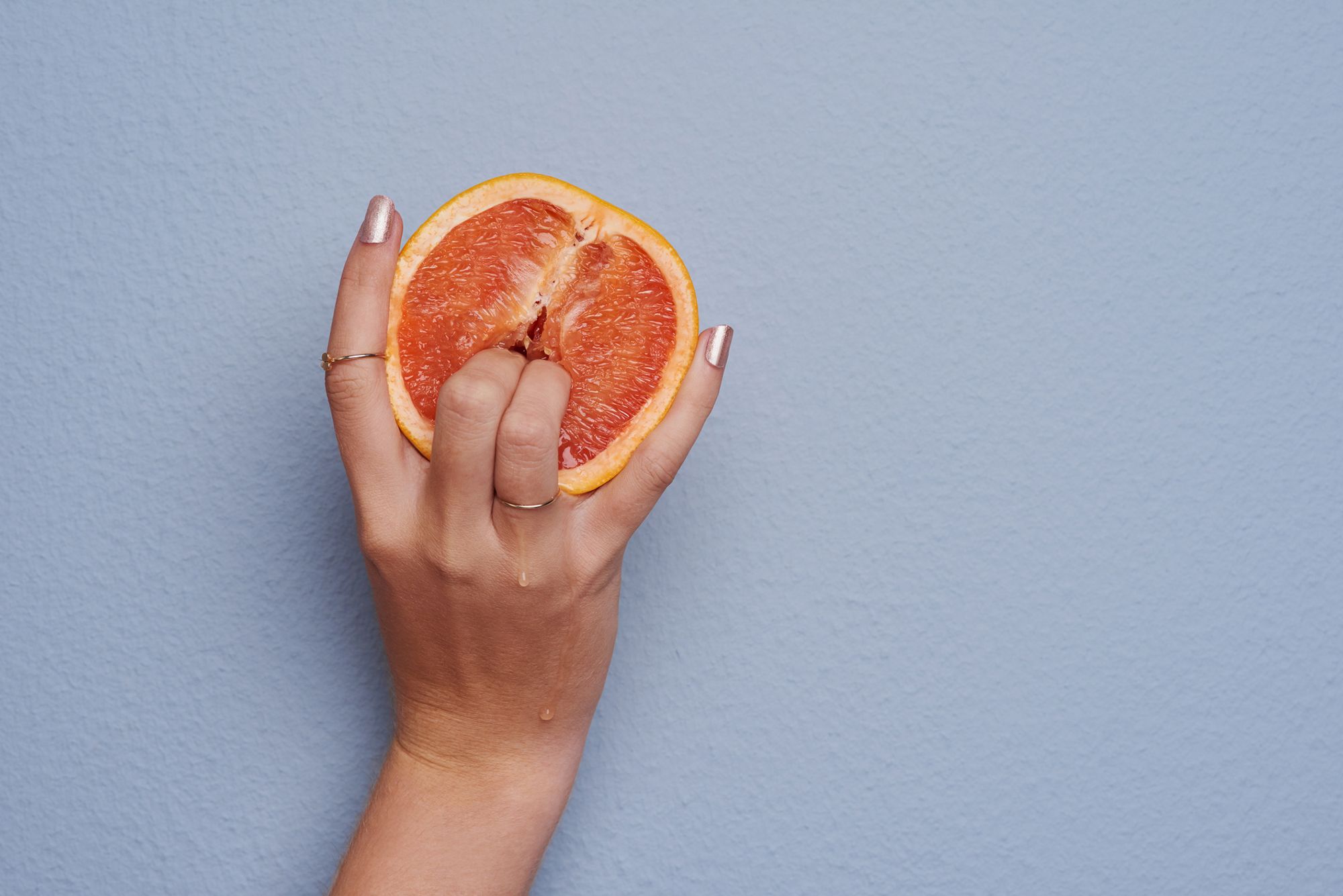 Zwei Finger, die in eine halbe Orange eingeführt werden