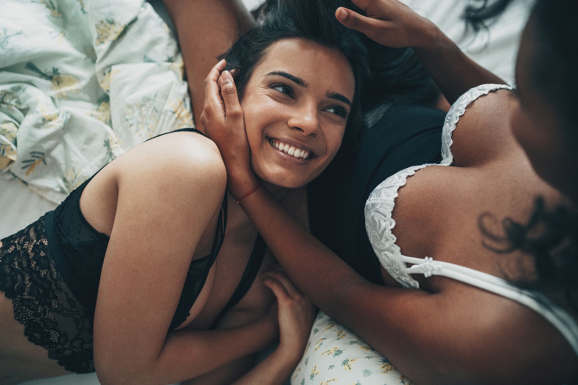 2 Frauen in Unterwäsche liegen im Bett, eine hat dem Kopf im Schoß der anderen