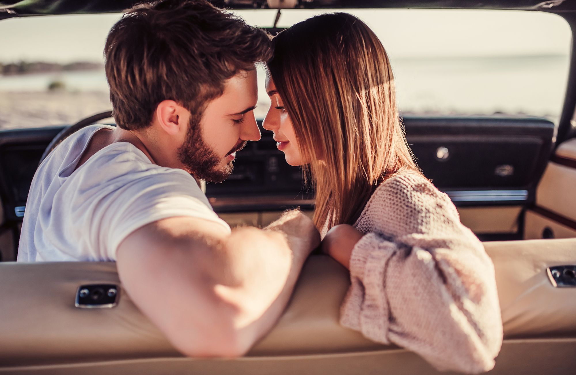 Junger Mann und junge Frau sind kurz davor, sich im Auto zu küssen