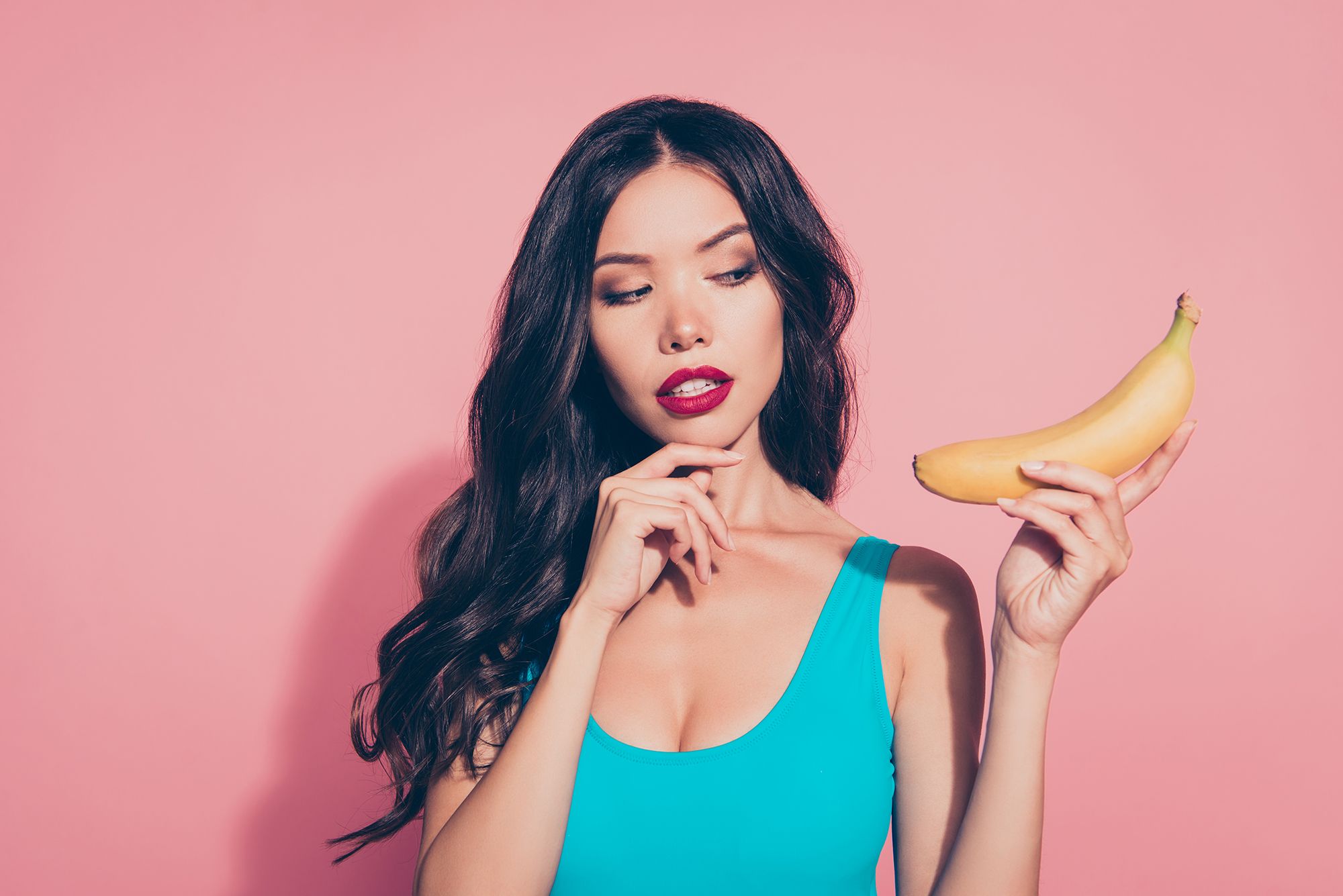 Frau hält eine Banane in der Hand und schaut nachdenklich