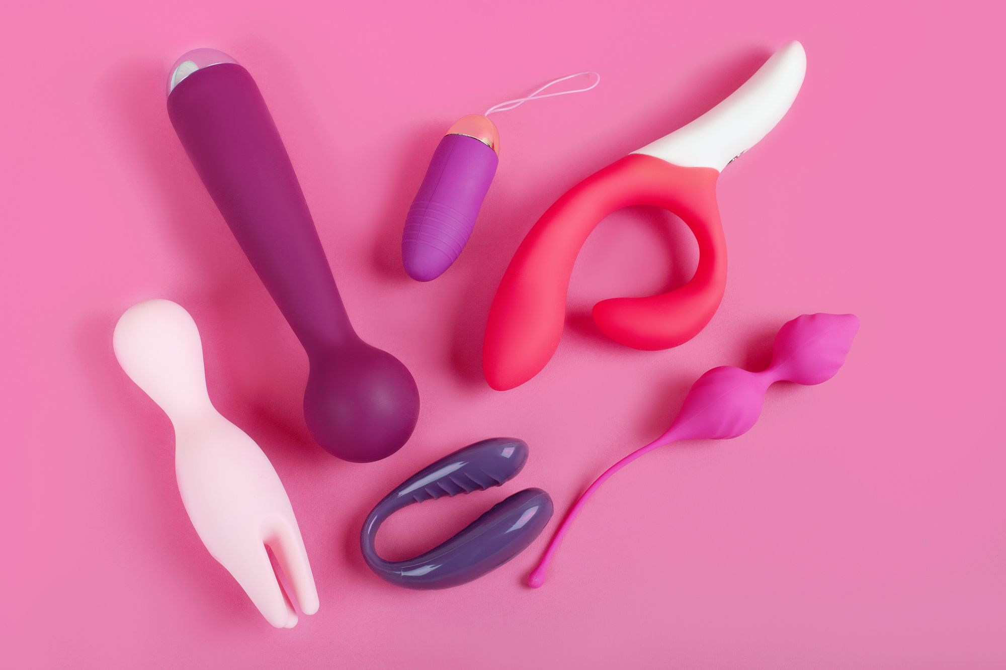 Verschiedene Sextoys auf pinkem Hintergrund