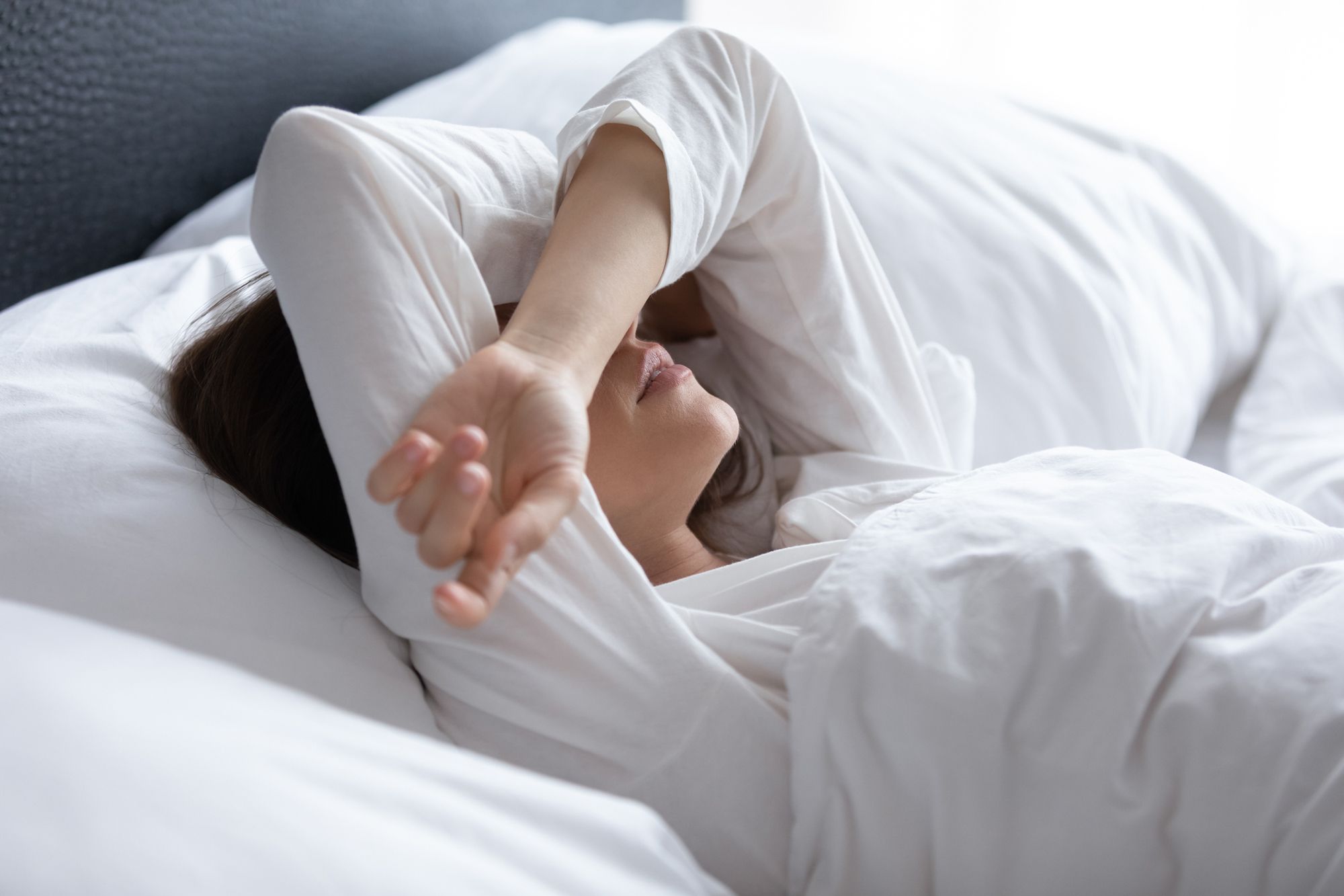 Frau liegt mit Kopfschmerzen im Bett