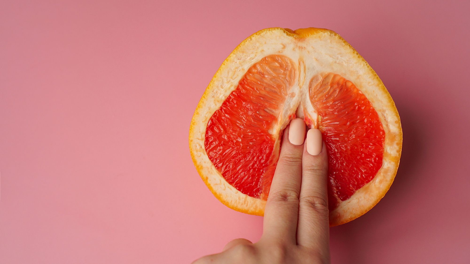 Frau führt 2 Finger in eine halbe Orange ein