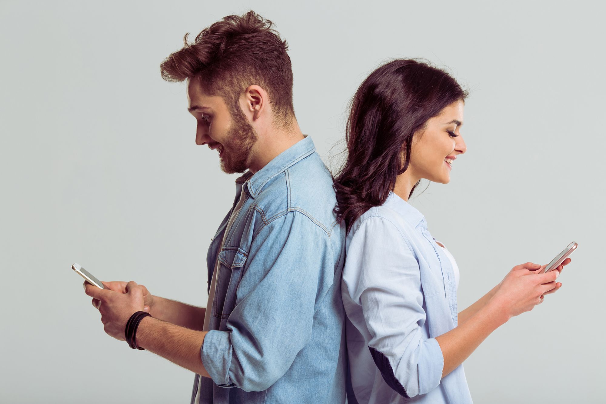 Mann und Frau stehen Rücken an Rücken und haben Handys in der Hand
