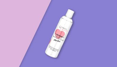 Gleit- und Erlebnisgel '2 become 1' Aloe Vera von Romance for Charity auf rosa-lilanem Hintergund