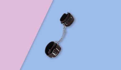 Schwarze Spreizstange mit Fußfesseln von EIS auf rosa-blauem Hintergrund