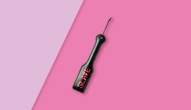 Schwarzer BDSM Paddle mit Aufschrift SLAVE auf rosa-pink geteiltem Hintergrund
