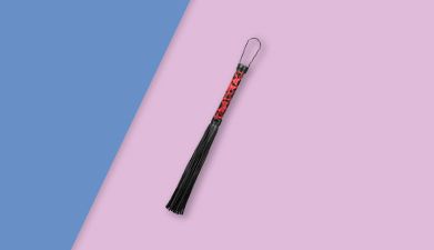 Schwarz-rote BDSM Peitsche mit XXL Riemen von EIS auf blau-rosa geteiltem Hintergrund