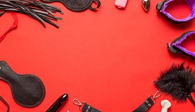 BDSM Zubehör das auf einer roten Fläche kreisförmig am Bildrand liegt