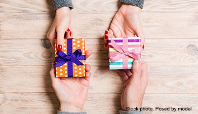 Männer- und Frauenhände, die zwei Geschenke untereinander austauschen