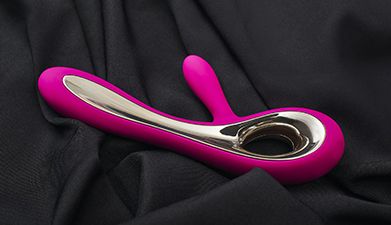 Ein gold-pinker G-Punkt Dildo der auf einem schwarzen Tuch liegt