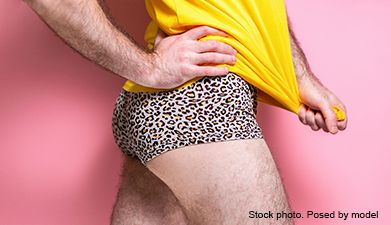 Ein Ausschnitt eines Mannes, der seitlich steht und einen Leoparden-Slip und ein gelbes Shirt trägt