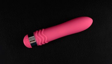 Ein pinker Vibrator vor einem schwarzen Hintergrund