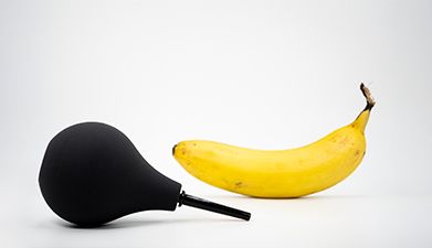 Eine Banane und ein schwarzer Klistier vor einem weißen Hintergrund