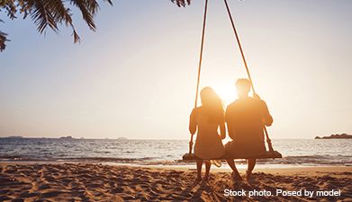 Ein Paar das auf einer Schaukel an einem Strand sitzt