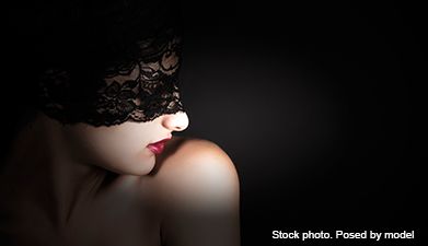 Nackte Frau mit roten Lippen und schwarzer Spitzenmaske auf schwarzem Hintergrund