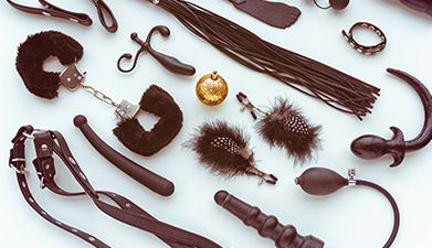 Schwarze BDSM Sextoys die angeordnet nebeneinander liegen auf einem weißen Hintergrund