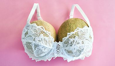 Zwei Galiamelonen in einem weißen BH vor einem rosanem Hintergrund