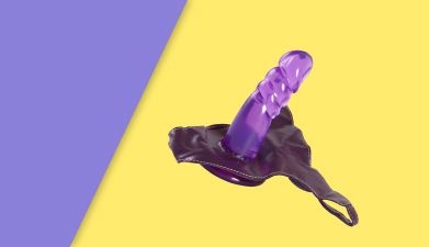 Ein lila Strap On Dildo vor einem lila-gelben Hintergrund