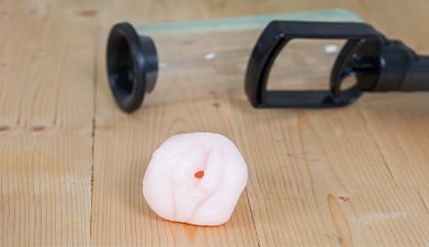 Eine Taschenmuschi und eine Penispumpe die auf einem Holzboden liegen