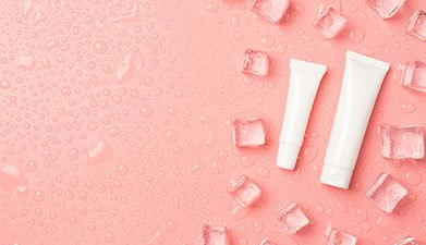 Zwei verschieden große weiße Tuben mit Eiswürfeln drum herum vor einem lachsfarbenem Hintergrund