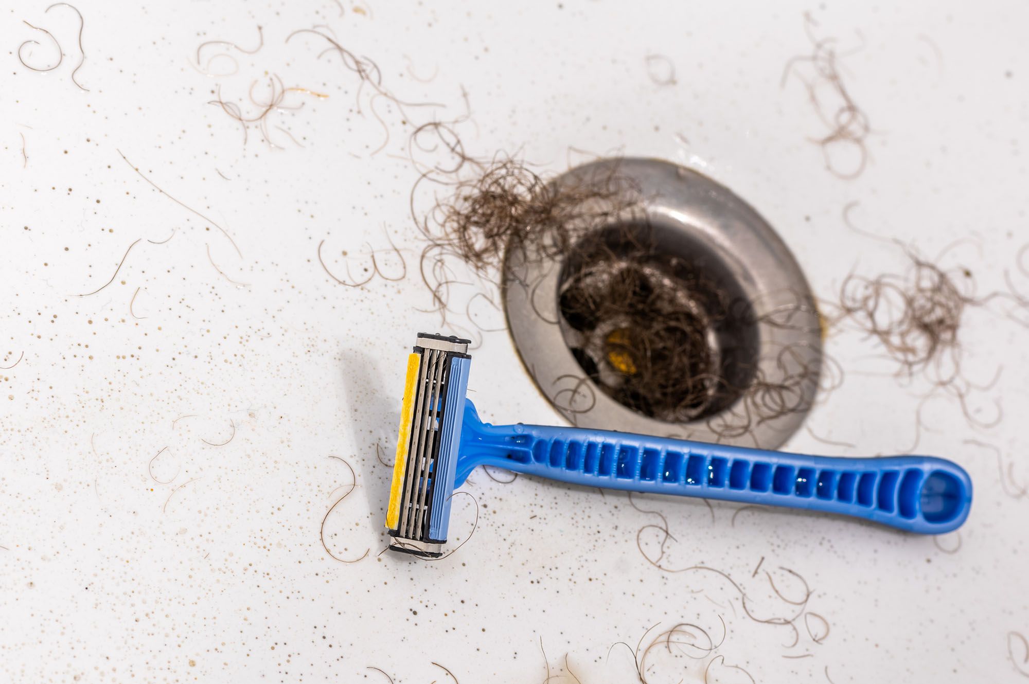 Rasierer in einem Waschbecken mit Haaren