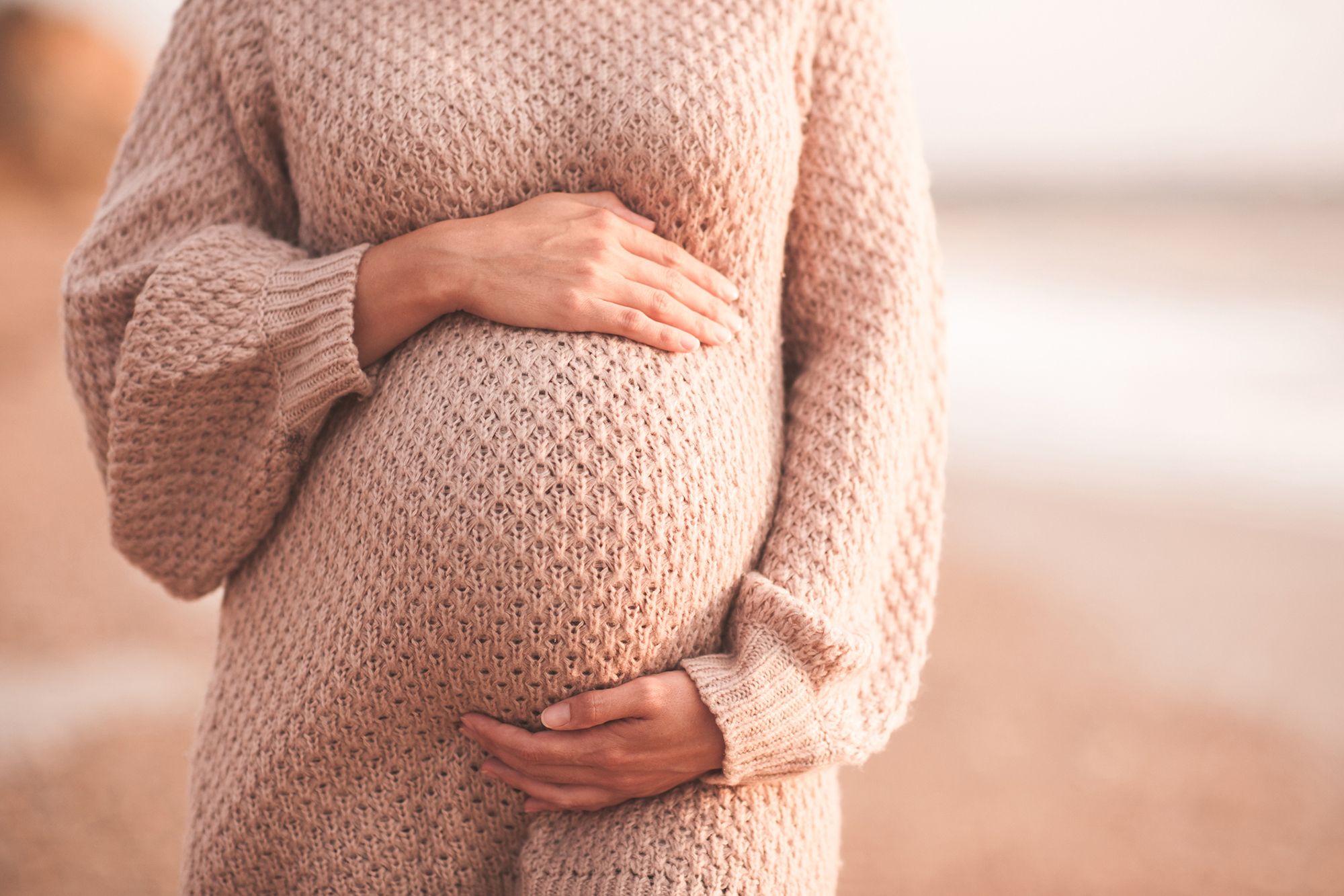 Schwangere Frau umfasst ihren Bauch