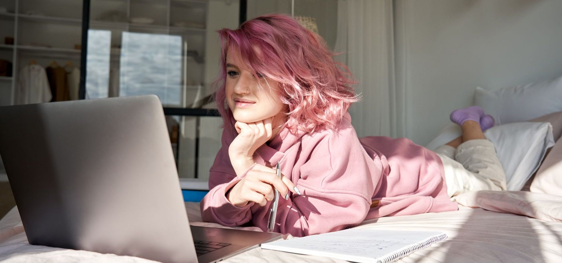 Frau liegt mit Laptop auf dem Bett