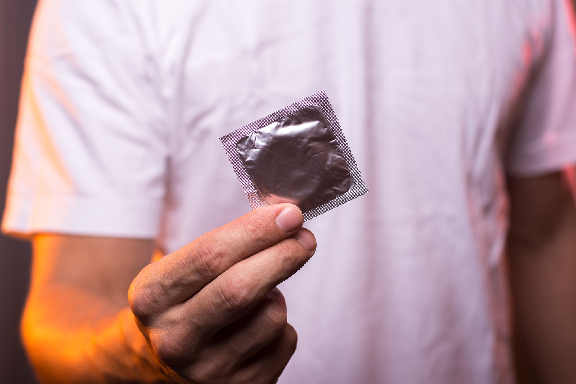 Mann hält eine Kondomverpackung in der Hand