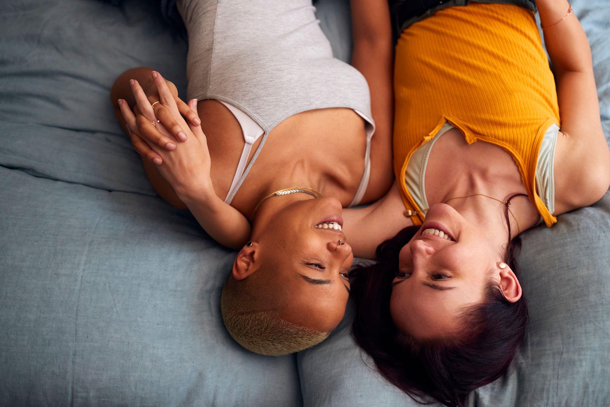 2 Frauen liegen auf einem Bett und schauen sich in die Augen