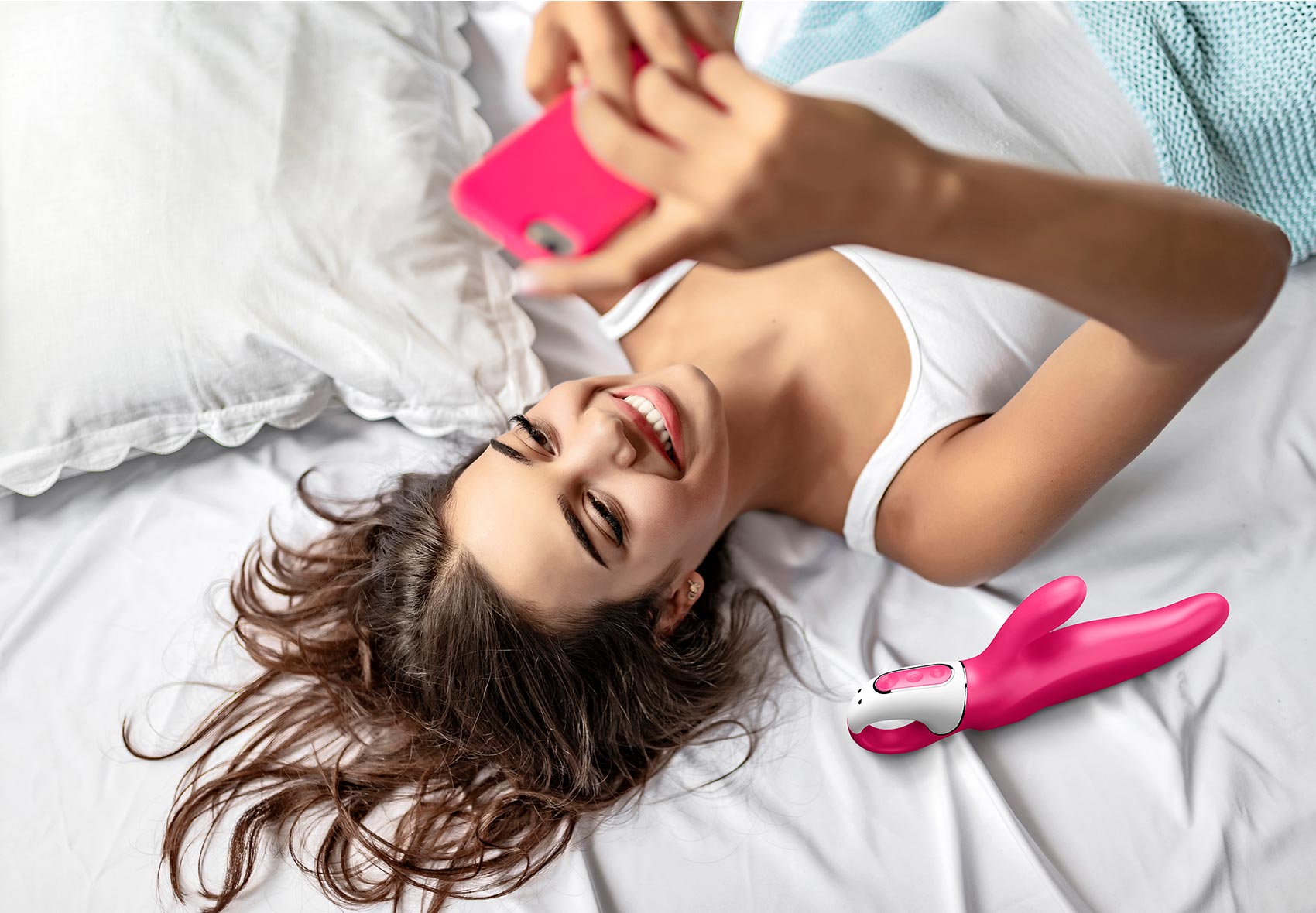 Frau im Bett mit Handy und Rabbitvibrator