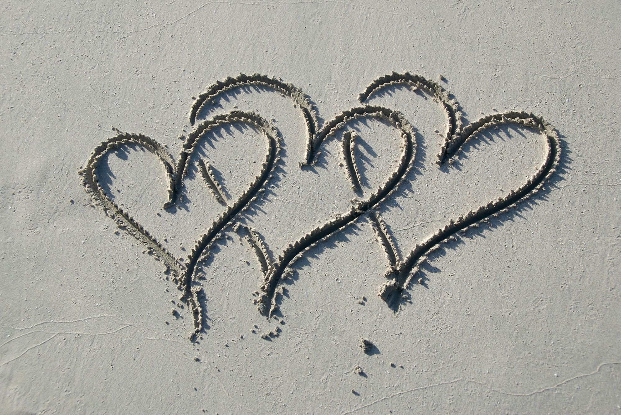Drei in den Sand gemalte Herzen