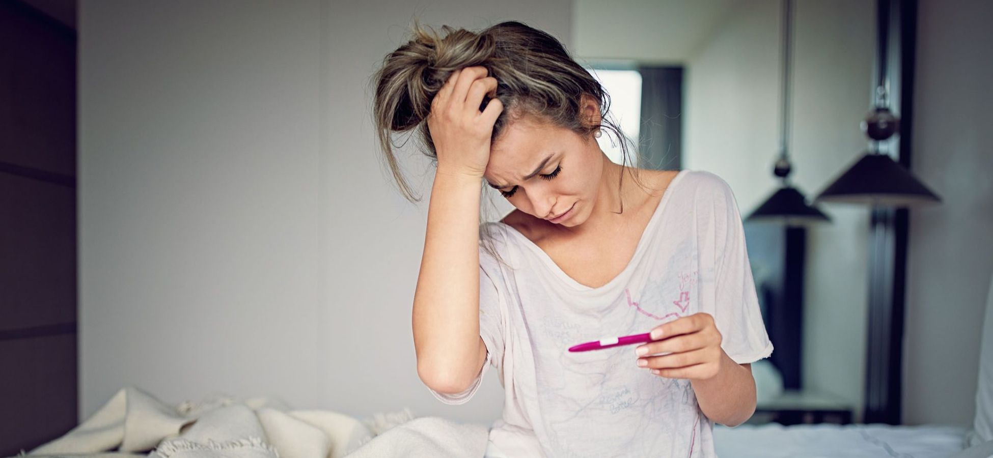 Frau schaut schockiert auf einen Schwangerschaftstest