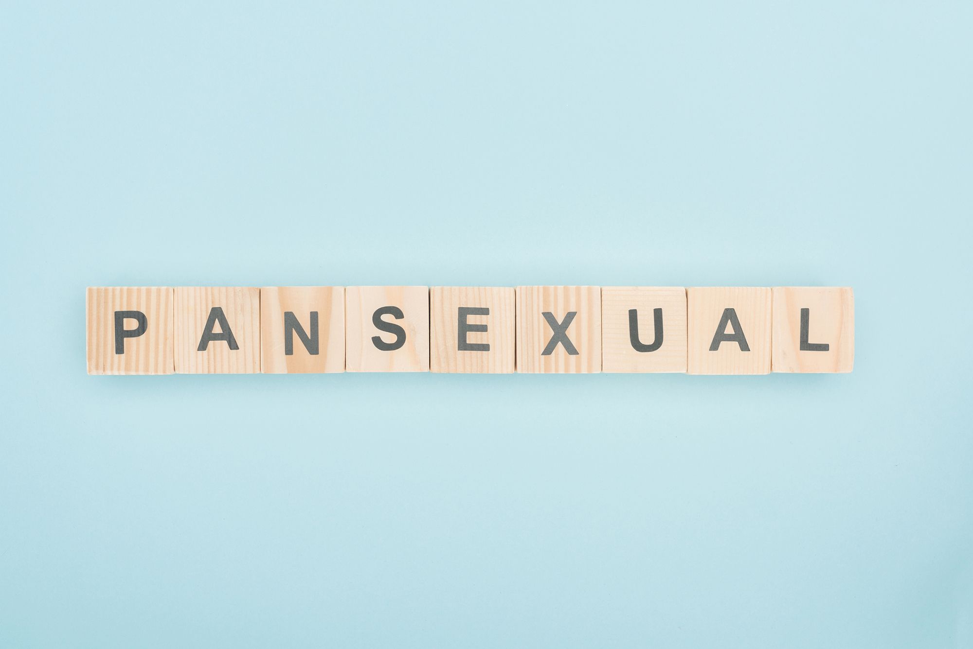 Holzbuchstaben mit der Aufschrift "Pansexual" vor hellblauem Hintergrund