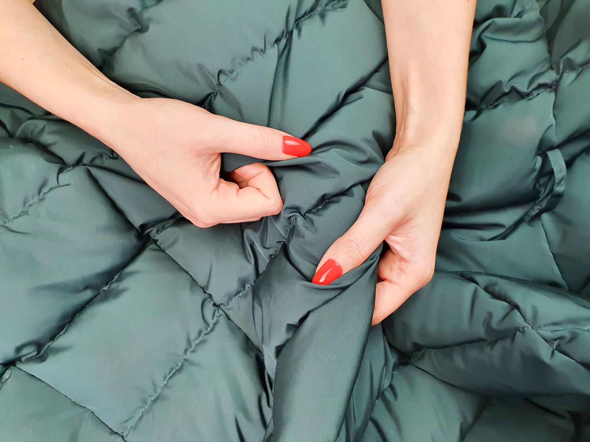 Hände mit roten Fingernägeln krallen sich in eine Decke