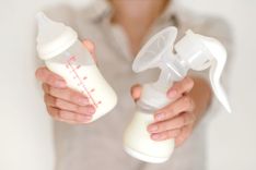 Frau hält in einer Hand ein Fläschchen und in der anderen eine Milchpumpe