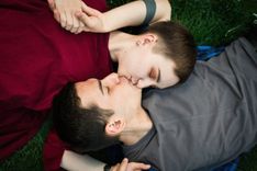 Paar umarmt und küsst sich liegend auf einer Wiese.