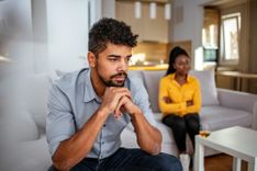 Paar sitzt mit Abstand auf dem Sofa