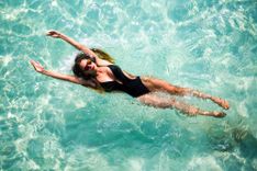 Frau mit schwarzem Badeanzug, die in einem Pool auf dem Rücken schwimmt