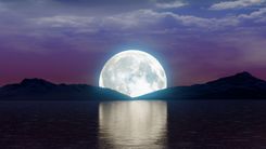 Der Mond geht über einem See unter und spiegelt sich im Wasser