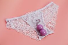 Pinke Liebeskugeln auf einem weißen Slip vor flamingofarbenem Hintergrund