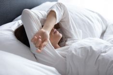 Frau liegt mit Kopfschmerzen im Bett