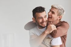 Ein schwuler Mann umarmt seinen Partner von hinten